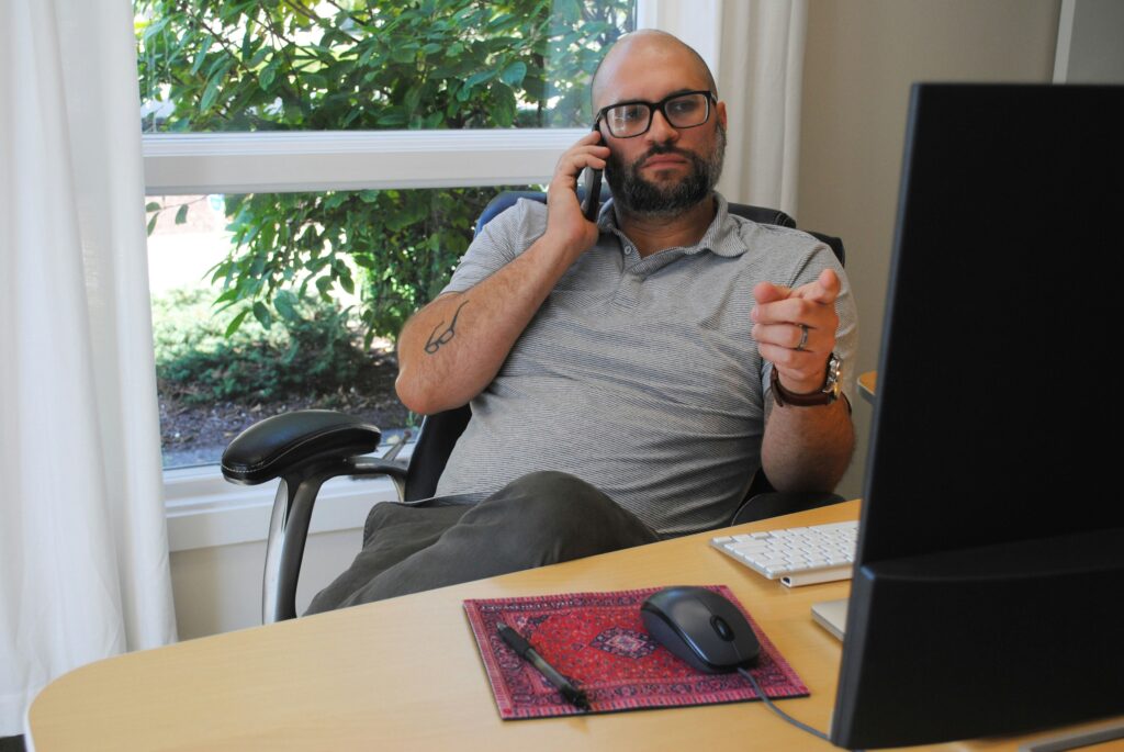 Professional business owner taking client phone call at organized home office desk with computer